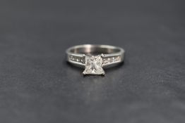 A platinum princess cut diamond solitaire ring having a 1ct princess cut diamond in a raised 4