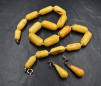 An egg yolk amber bead necklace having graduated cylindrical beads, on a white knotted cord, on a
