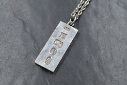 A silver ingot pendant having oversized 1977 hallmarks on a 31' silver rope chain, approx 54g total