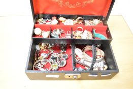 A black faux leather jewellery box, containing an assortment of costume jewellery, including