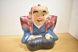 An interesting Japanese part-glazed pottery Fukusuke doll, formed as a seated jolly gentleman in