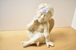 A decorative Victorian pottery cherub figurine with a crackle glaze finish, in a seated position,