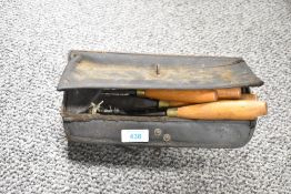 A vintage painted metal and leather tool box containing nine wood turning/carving chisels