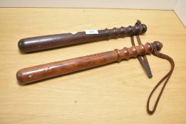 Two 20th-century wooden batons, featuring fluted turned handles and leather wrist straps,