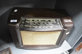 A vintage early -mid 20th century bakelite cased radio, with glass tuning scale and material speaker