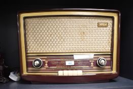 A Vintage Stella bakelite cased radio with woven material speaker grille and glass tuning scale with