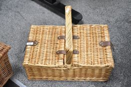 Two 20th-century wicker baskets, with hinged lids, to include a picnic basket example having a small