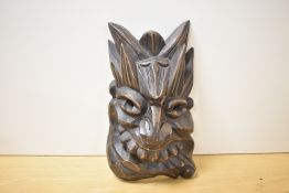 A decorative Chinese carved wooden mask, carved in high relief with grotesque features, 26.5cm