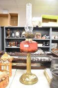 A Victorian brass oil lamp, having a cranberry glass reservoir with a fluted Corinthian-style