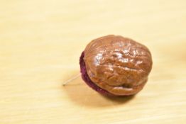 A small Victorian fancy work walnut shell pin cushion, a sweet, very small and tactile example,