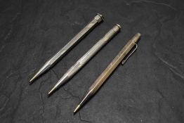 Three Yard o Led Sterling Silver pencils. One round, two hexagonal, all engine turned. One dated
