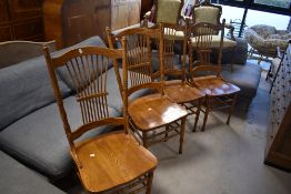 A set of four stained frame dining chairs in the colonial style having solid seats and spindle