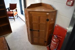 Workshop of Robert Mouseman Thompson of Kilburn; A golden oak wall corner cupboard, with panelled