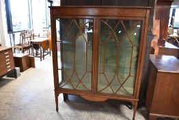 An Edwardian mahogany display cabinet having inlaid decoration and square tapered legs on spade