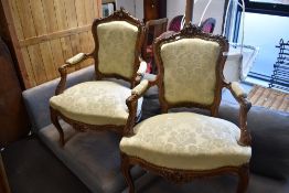 A pair of walnut framed easy armchairs in the French style