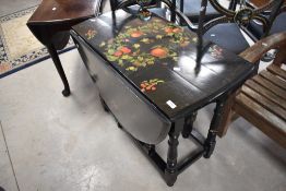 A Victorian style ebonised table having turned gateleg and painted fruit decoration