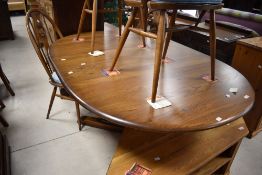 A modern Ercol extending oval dining table and four (two plus two) swan back chairs, all in mid