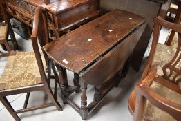 A traditional oak dining table having drop leaves and turned gateleg