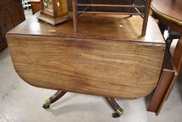 A 19th Century mahogany dining table in the Regency style having drop flaps and drawer to each end