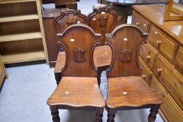 TWO pairs of 19th Century mahogany hall chairs having shaped shield backs