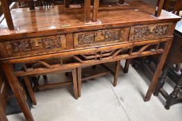 An Oriental fruitwood side table having triple frieze drawers with carved foliate fronts, dimensions
