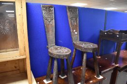 A pair of period oak hall chairs having carved coat of arms to seat and back , on rustic splay legs,