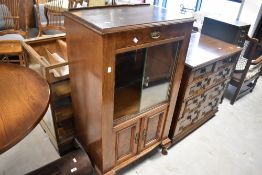An early 20th Century part walnut display cabinet having upper drawer over sliding glass door