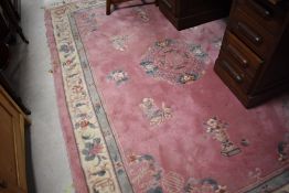 A large Chinese pink ground rug/carpet of traditional design with fringed ends 274cm x 182cm