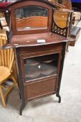 An Edwardian mahogany display cabinet of Art Nouveau influence having shaped shelves and mirror