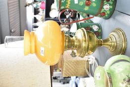 A 20th-century brass Duplex oil lamp, having an orb-shaped amber glass shade, marked, 52cm tall,