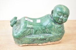 A 20th-century Chinese ceramic 'boy' head rest, hand formed and glazed in a spinach jade-style