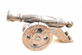 A large decorative 20th-century handcarved wooden cannon on wheels, with carved decoration along the