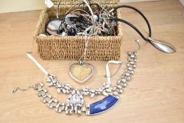 A wicker box containing an assortment of costume jewellery, including large statement pieces, beaded