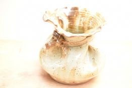 A 20th century studio pottery stoneware vase, formed as a loosely tied sack with mottled buff glaze,