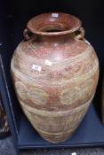 A large 20th-century earthenware palm wine pot with twin loop handles, featuring a bulbous