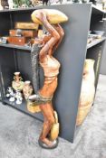 A tall 20th-century African Tribal Art hand-carved hardwood statue of a female drinking from a