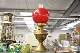 A Victorian brass and glass oil lamp, having ruby red glass globe shade, a clear glass chimney and