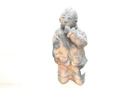 A 20th-century Chinese hand formed terracotta sculpture depicting a stylised young boy in