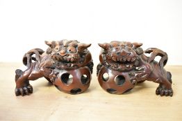 A pair of 20th-century hard wood carved Foo-dog mantel statues, traditionally displayed in pairs