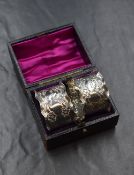 A cased pair of Victorian silver napkin rings, having flared lobed rims with decorative floral