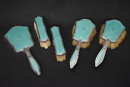 A George V silver and guilloche enamel vanity set, comprising a hand mirror, two clothes brushes and