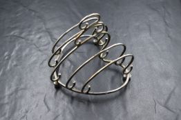 An Edwardian silver toast rack, of heart form with five sections, raised on three ball feet, marks
