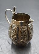 An Eastern white metal jug, of bulbous lobed form having panels of embossed scenes including animals