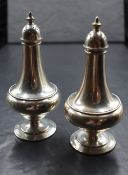 A pair of 20th century silver pepperettes, of bulbous form having final tops with bead decoration to