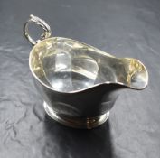 A George V silver sauce boat, having a moulded rim, generous spout opposed by a scroll handle and