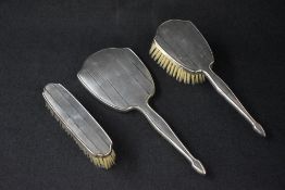 A George VI silver mounted three piece vanity set, comprising a hairbrush, hand mirror and clothes