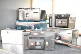 A collection of five compact film cameras. A Vivitar EZ200 35mm film camera, a Hanimex 35hs 35mm fi