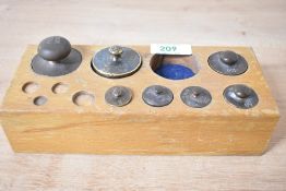 A part set of 20th-century bronze apothecary weights in a wood block case, featuring seven