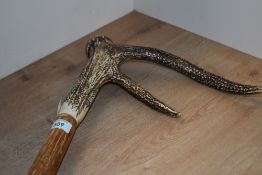 A large walking stick with 2 point antler handle measuring 151cm long and bearing transfer images of