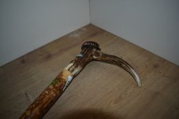 A large walking stick with antler handle measuring 124 cm long and bearing transfer images of a